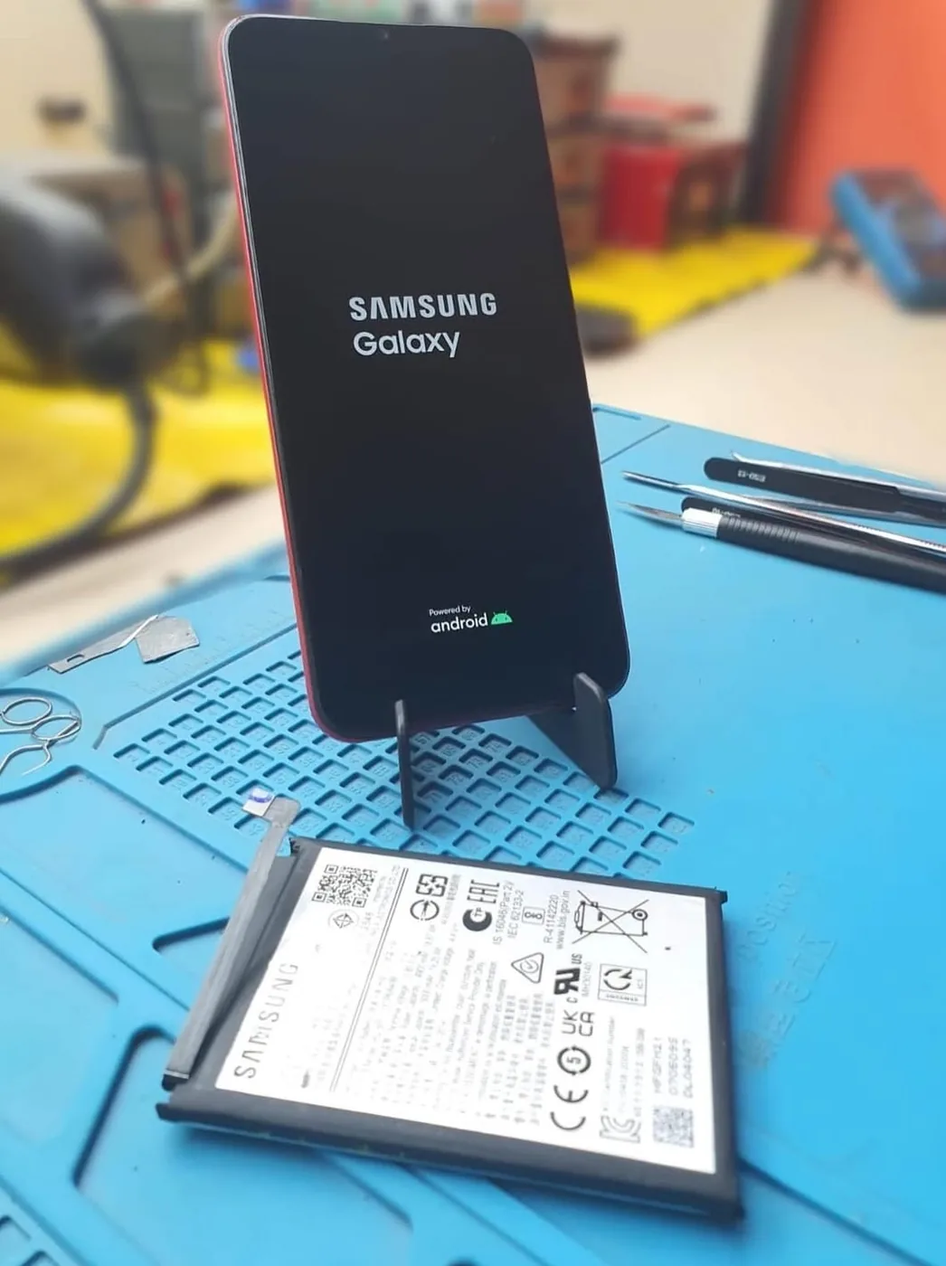 Samsung Galaxy A03s ligado após troca de bateria, com bateria substituída na bancada