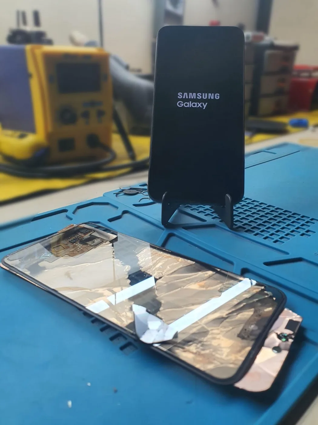 Samsung Galaxy A54 ligado após troca de tela, com conjunto antigo na bancada