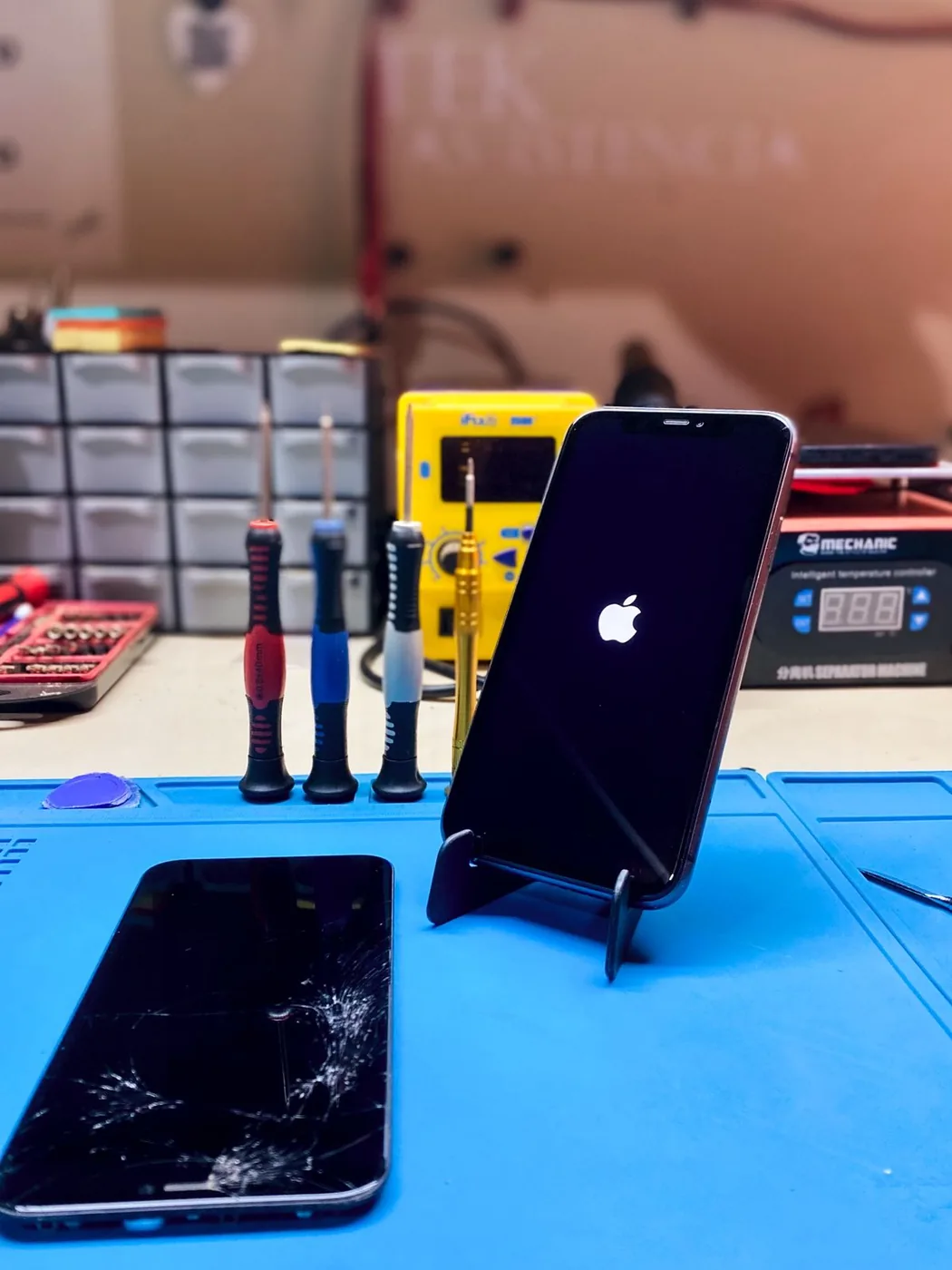iPhone 11 ligado após troca de tela, com tela quebrada em primeiro plano