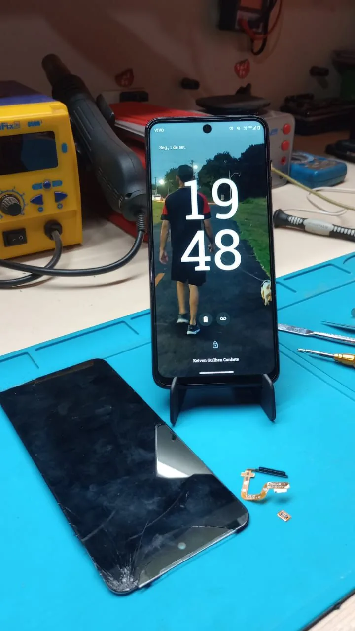 Motorola Moto G53 funcionando após troca de tela, com tela quebrada sobre a bancada