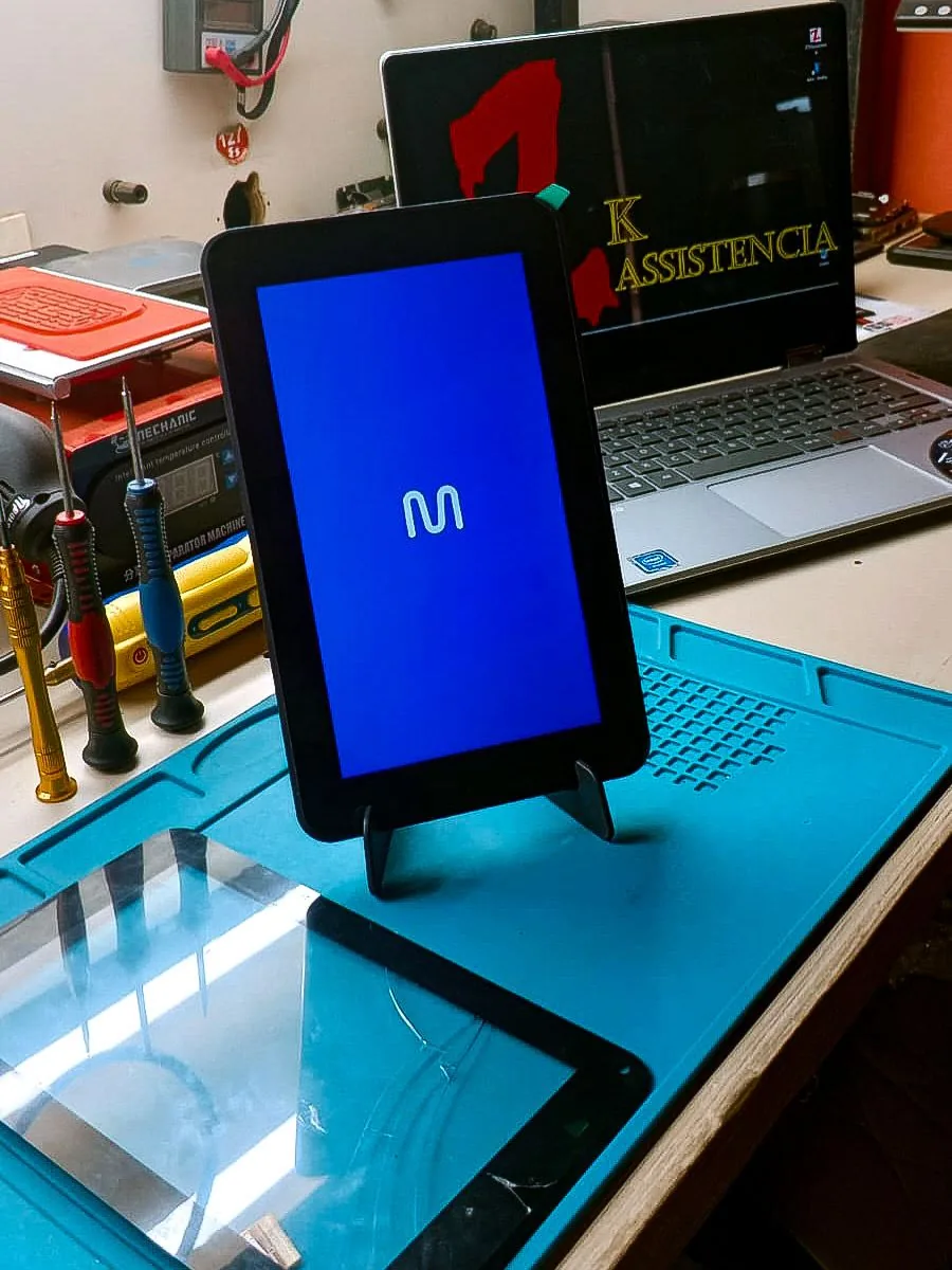 Tablet Multi M7 ligado após troca de tela, com tela antiga sobre a bancada